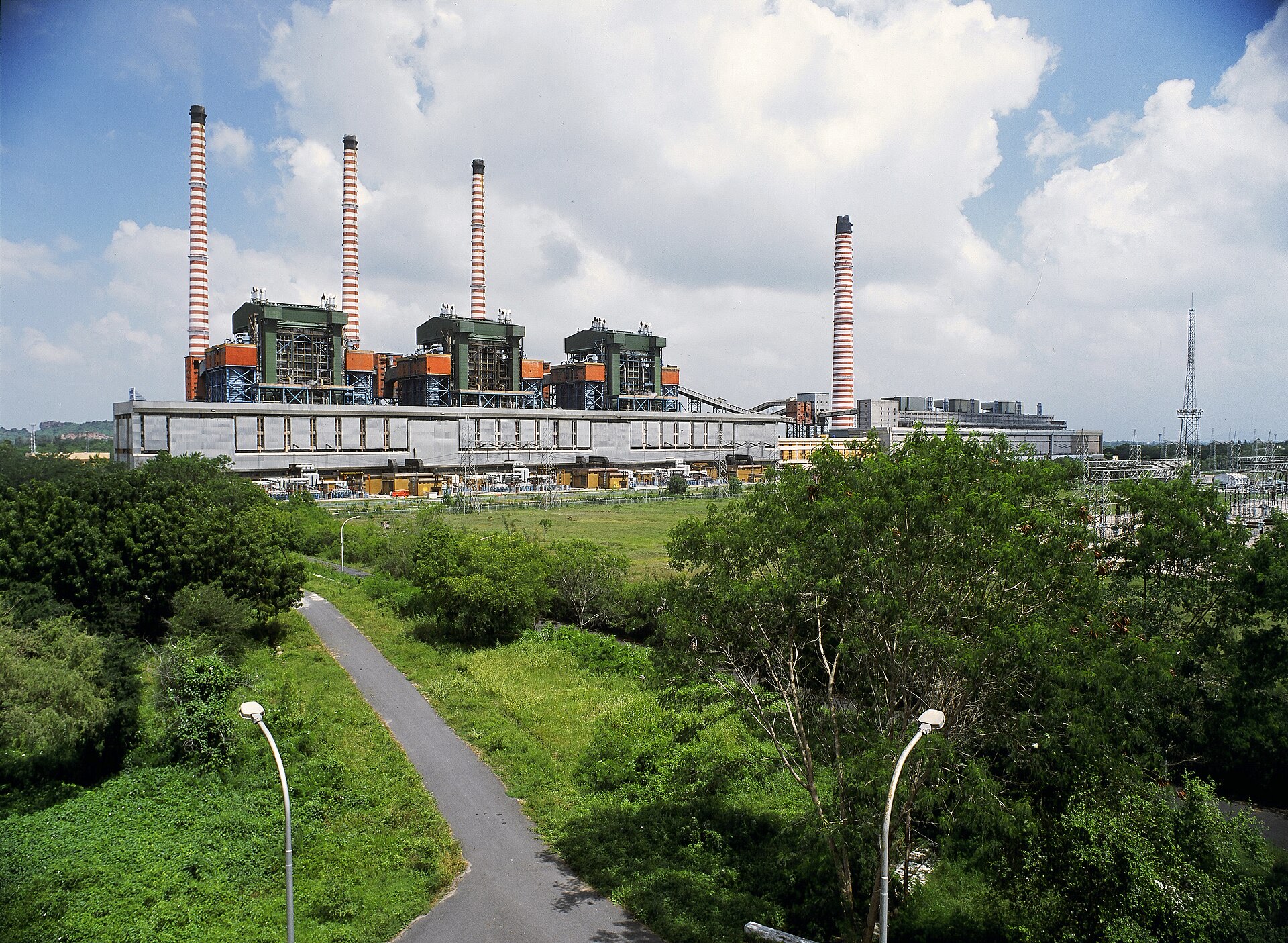 The NTPC Ramagundam thermal power complex with its striped chimneys under monsoon clouds